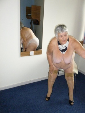Obese old woman Grandma Libby lays her floppy tits on a desk while undressing