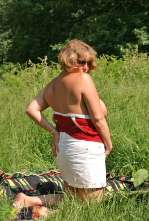Fat mature lady Curvy Claire uncovers her large tits and big ass in a field