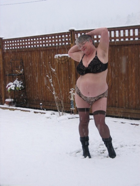 Naughty granny Girdle Goddess strips to her stockings and boots while it snows