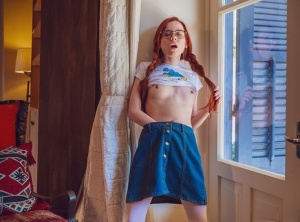 Young redhead Sherice keeps her glasses on while getting naked to masturbate
