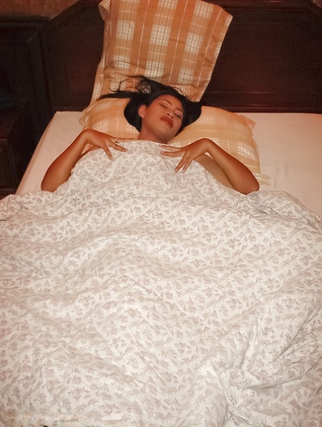 Busty asian babe slipping off her clothes and posing naked on the bed