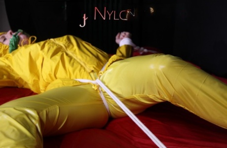 Fair skinned female is gagged and restrained in yellow nylon rain wear 14715216